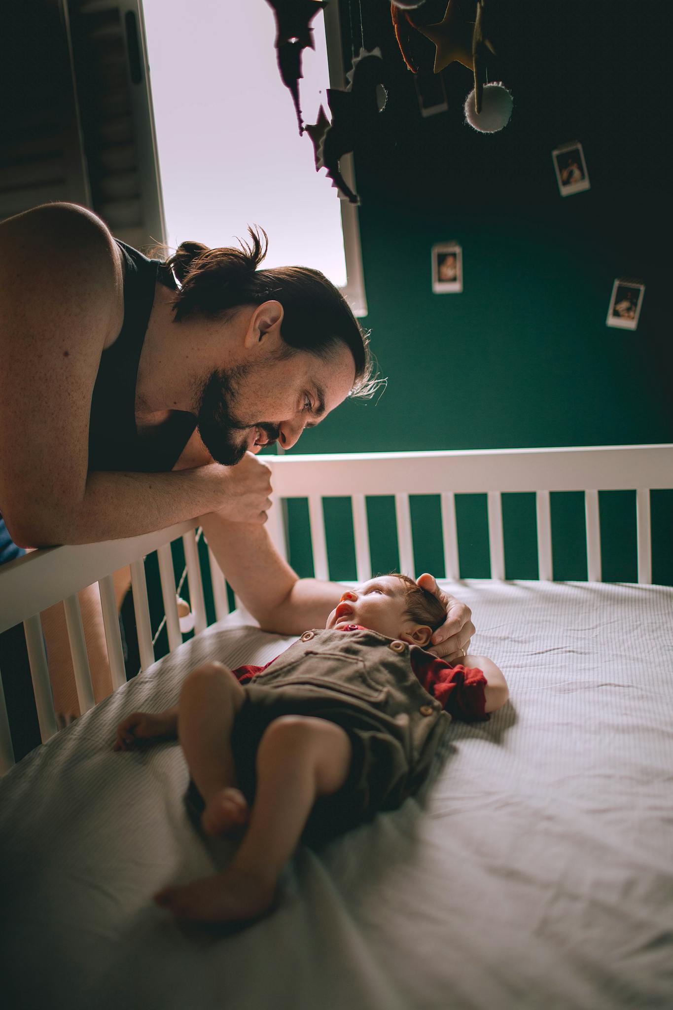 A father tenderly looks at his baby in a crib, showcasing love and fatherhood.