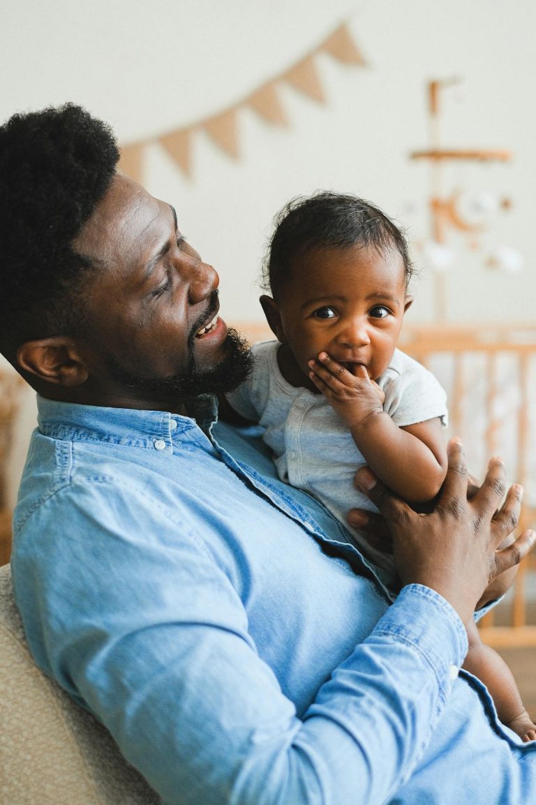 African American father holds baby with warmth and care. Captures tender fatherhood.